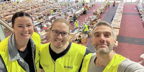 Etienne and two other volunteers in Lifeline vests, in a hall full of book tables